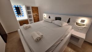 a bedroom with a white bed with towels on it at Chryssa Bungalows in Andros