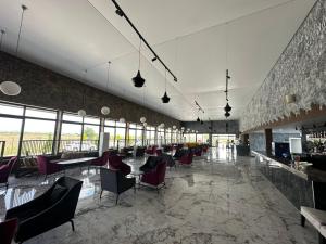 a restaurant with chairs and tables and windows at Palmora Lara Hotel in Aksu