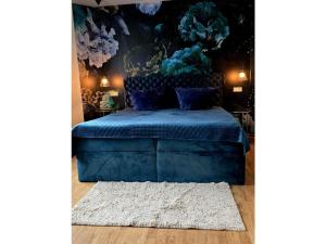 a bedroom with a blue bed with a painting on the wall at Ferienwohnung Das grüne Haus in Byhlen