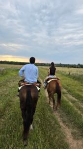 two people riding horses down a dirt road at Complejo La Conquista in Goya
