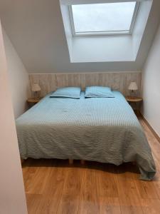 a bedroom with a bed with two lamps and a window at Le Gîte des Fèves in Lecelles