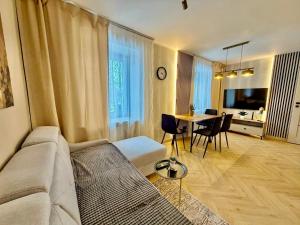 a living room with a couch and a table with chairs at Fly Apartment Modlin by JumpInHere in Nowy Dwór Mazowiecki