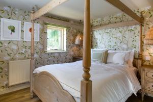 a bedroom with a four poster bed with floral wallpaper at Harts Leap in Redmarley DʼAbitot