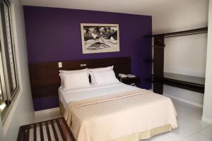 a bedroom with a bed with a purple wall at Porto Center Hotel in Luís Eduardo Magalhães +47 photos