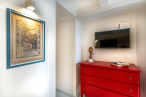 a red dresser with a painting and a tv on a wall at Dimora Filangieri in Massa Lubrense