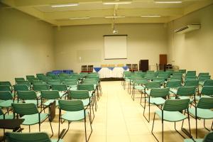 an empty room with green chairs and a screen at Porto Center Hotel in Luís Eduardo Magalhães