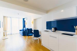 a kitchen with blue and white cabinets and blue chairs at Hotel sea view in Batumi
