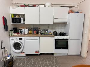 a kitchen with white cabinets and a washer and dryer at Affordable, fully equipped practical housing! in Laivaniemi