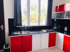 a kitchen with red and white cabinets and a sink at Marissa Villa in Katunayaka