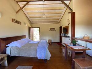a bedroom with a bed and a table in it at Chalé Serra dos Encantos in Lavras Novas