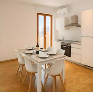 a white kitchen with a table and white chairs at Penthouse Station luxury apts Le dimore in Brindisi