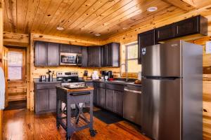 a kitchen with wooden cabinets and a stainless steel refrigerator at Take It Easy - 5 Star Family Cabin View Hot Tub FirePit Pools Bears in Gatlinburg