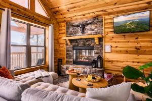 a living room with a stone fireplace in a log cabin at Take It Easy - 5 Star Family Cabin View Hot Tub FirePit Pools Bears in Gatlinburg