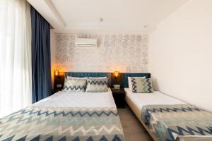 two beds in a small room with curtains at Palmora Lara Hotel in Aksu +39 photos