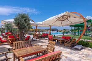 a patio with tables and chairs and an umbrella at Palmora Lara Hotel in Aksu