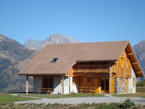 a large wooden house with mountains in the background at Les Chalets du Choumeau in Saint-Léger-les-Mélèzes