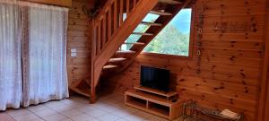 a living room with a staircase and a television at Les Chalets du Choumeau in Saint-Léger-les-Mélèzes
