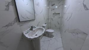a white bathroom with a sink and a toilet at Hôtel Sable d'Or in Tan-Tan +47 photos