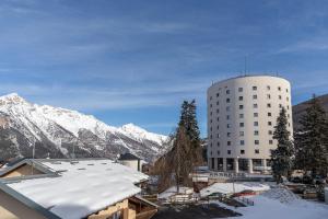 a white building with snow covered mountains in the background at Hotel la Torre in Sauze dʼOulx