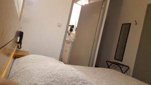 a small bedroom with a bed and a mirror at Hotel Glaizette in LʼArgentière-la-Bessée