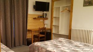 a bedroom with a bed and a desk with a television at Hotel Glaizette in LʼArgentière-la-Bessée