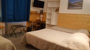 a bedroom with two beds and a blue curtain at Hotel Glaizette in LʼArgentière-la-Bessée