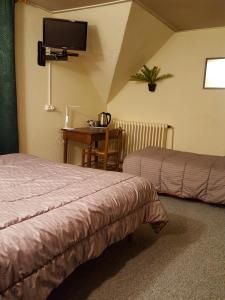a hotel room with two beds and a table with a tv at Hotel Glaizette in LʼArgentière-la-Bessée
