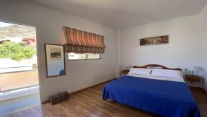 a bedroom with a blue bed and a large window at El Chorro Atico in Calera