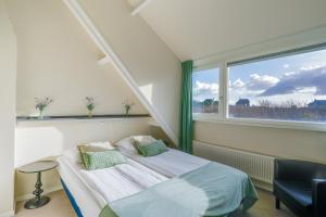 a bedroom with a bed and a large window at Appartementen Parkzicht in Bergen aan Zee