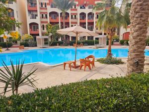 a swimming pool with a table and an umbrella at Ground floor Garden & Pool & Beach Studio in Sharm El Sheikh