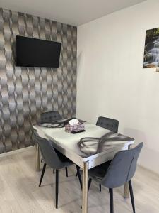 a dining room table with chairs and a television on a wall at Happy apartment 1 in Roşu