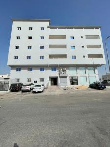a large white building with cars parked in a parking lot at Grandstay in Al Hofuf