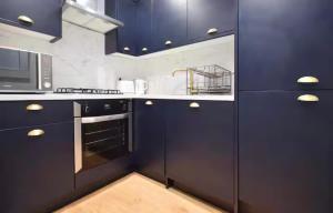 a kitchen with navy blue cabinets and a microwave at Portside Apartment in Greenock