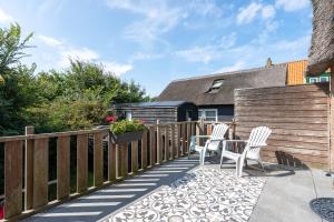 a patio with two chairs and a fence at Appartementen Parkzicht in Bergen aan Zee
