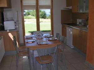 a kitchen with a wooden table with chairs and a table and a window at Les Chalets du Choumeau in Saint-Léger-les-Mélèzes