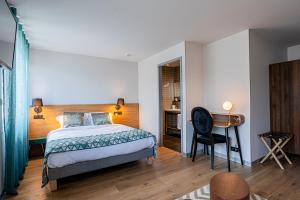a bedroom with a bed and a desk at Hôtel L'Ouvrée in Savigny-lès-Beaune