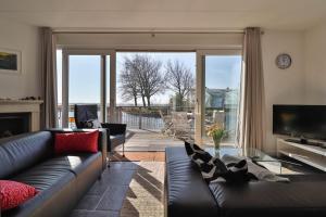 a living room with a couch and a television at Villa Seaview met Sauna in Makkum