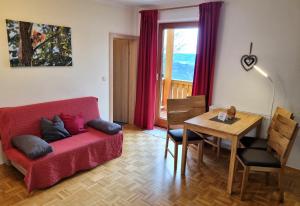 a living room with a red couch and a table at Bauernhof Pension Juri in Obergösel