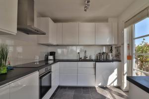a white kitchen with white cabinets and a window at Villa Seaview met Sauna in Makkum