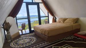 a bedroom with a bed and a large window at Villa Annisa 2 in Alahanpanjang