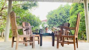 a table with three chairs and a person sitting at it at Kanchi's please in Udawalawe
