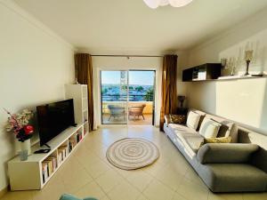a living room with a couch and a television at The Seashell Armação Beach Apartment in Armação de Pêra
