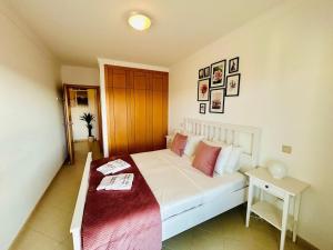 a bedroom with a white bed and a table at The Seashell Armação Beach Apartment in Armação de Pêra