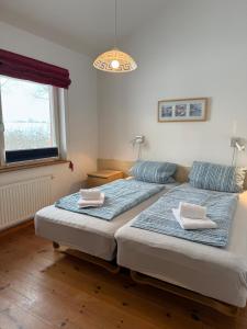 two twin beds in a room with a window at Lachmöwe in Munkbrarup