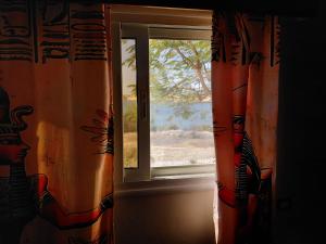 a window with orange curtains in a room at Amon guest house in Abu Simbel