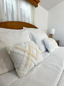 a white bed with white pillows with a cross on it at Maria apartment in Ponta do Sol