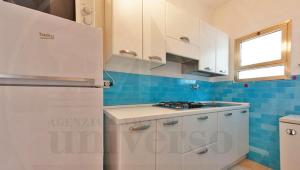 a kitchen with white cabinets and a refrigerator at Bungalow Baleno in Eraclea Mare