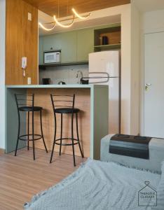 a kitchen with three bar stools and a refrigerator at Refugio Premium 2 Quartos 1 Suite WiFi Ar e Garagem in Pelotas