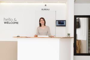 a woman standing at a reception desk in a office at Hotel Parisien in Menton