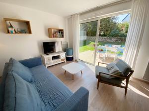 a living room with a blue couch and a tv at RIVAGE - Villa 6 pièces, Jardin, Calme - S28 in Carnac